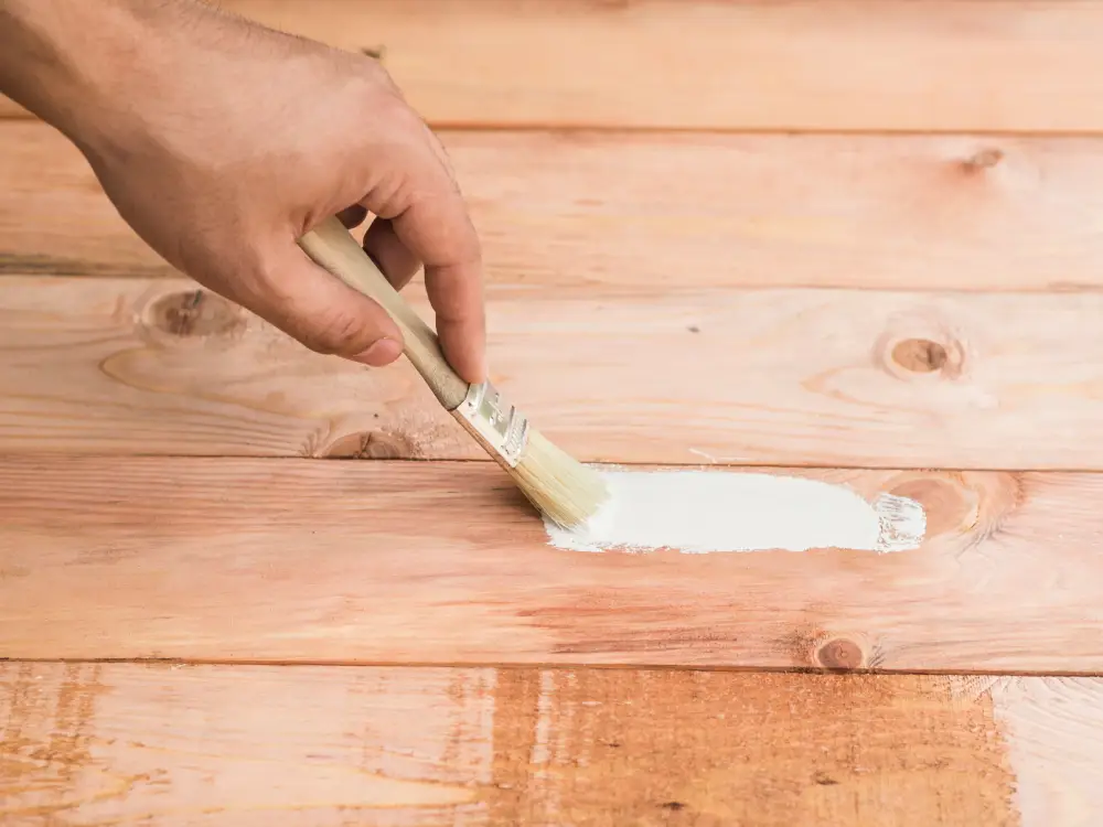 A worker painting on the wooden flooring