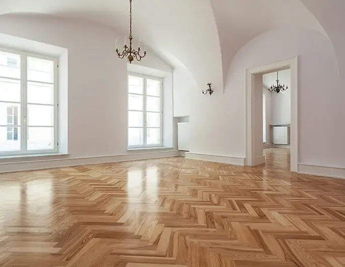 Elegant room with vaulted white ceilings featuring pristine oak herringbone parquet hardwood floors