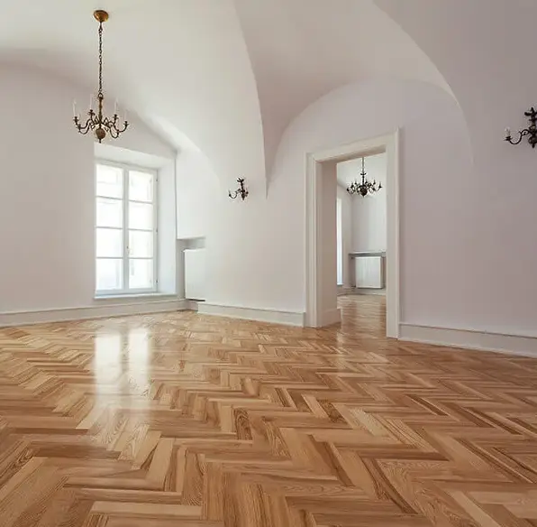 Elegant room with vaulted white ceilings featuring pristine oak herringbone parquet hardwood floors
